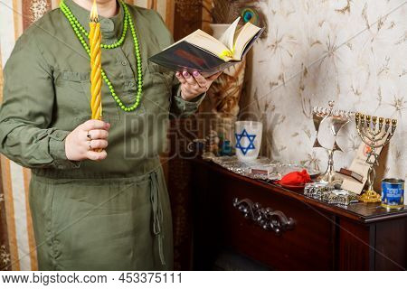 A Jewish Woman Without A Face With Awdala Candles And A Siddur In Her Hands. Horizontal Photo