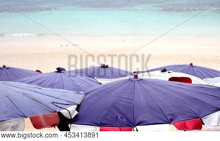 Purple Umbrellas On The Beach With Soft Focus Of Sea In The Background