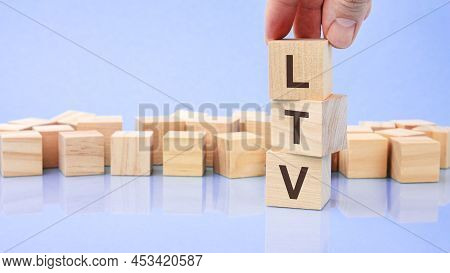 Hand Holding Wood Cube Block With Ltv Text. The Inscription On The Cubes Is Reflected From The Surfa