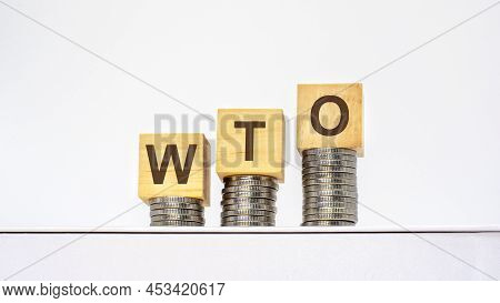 Rising Stacks Of Coins With The Letters Wto On The Wooden Cubes, White Background, Business And Fina
