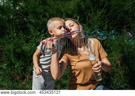 Happy Family Blowing Soap Bubbles In The Backyard, Garden. Child Kid Boy Blowing Soap Bubbles. Happy