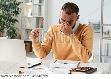 Tired Young Middle Eastern Businessman Holding Eyeglasses And Rubbing Bridge Of Nose While Overworki