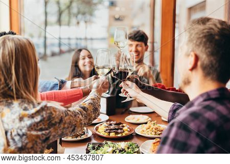 Group Of Friends Toasting With Glasses Of Wine Inside A Restaurant
