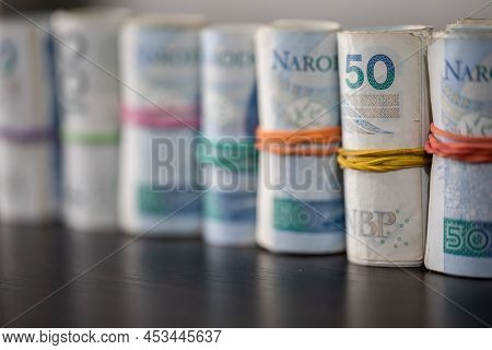 The Banknotes Rolled And Tied Together With A Rubber Band Stand On The Table Top.
