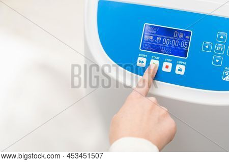 Woman Pushes Button Start On The Centrifuge For Sample Preparation. Dna, Oncology Marker Analysis In