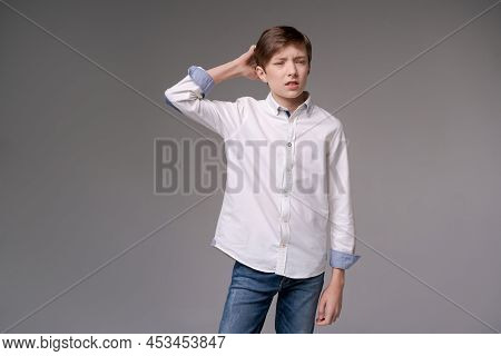 Thoughtful Young Teen Man Holding Hand On Chin Indecision Pose In White Shirtisolated On Gray Studio