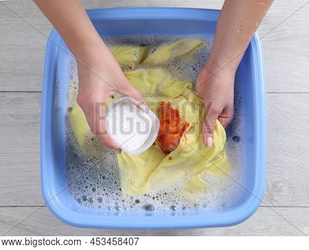 Woman Adding Powdered Detergent Into Basin With Clothes, Top View. Hand Washing Laundry