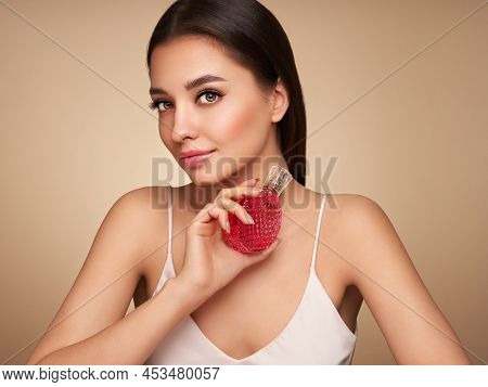 Young Beautiful Woman With A Bottle Of Perfume. Model With Healthy Skin, Close Up Portrait. Cosmetol