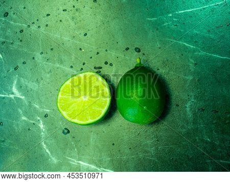 Top View, Limes And Limes Cut In Half (citrus Aurantiifolia), Placed On Black Marble Table, Isolate