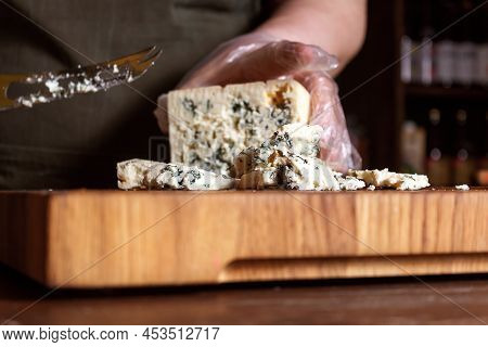 Cheese Store. Unrecognizable Saleswoman In Apron Slices Crumbly Blue Mold Roquefort Cheese With Spec
