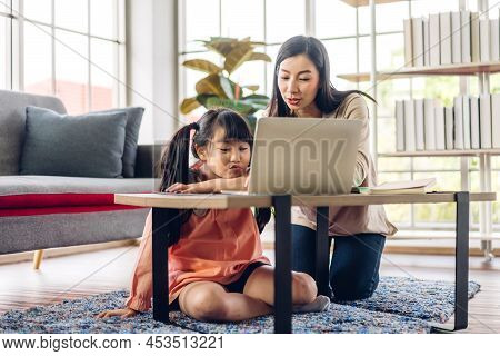 Mother And Asian Kid Little Girl Learning And Looking At Laptop Computer Making Homework Studying Wi