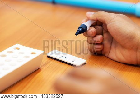 Close-up Hand Holding Buffer And Drop Mucus Sample Placed On Strip Of Antigen Test Kit (atk) For Cor