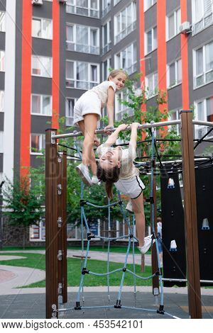 Two Pretty Teen Girls Playing On A Modern Playground In Identical Clothes. Sister, Bffs. Sisterhood,