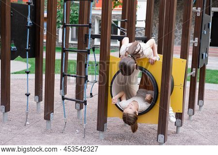 Two Pretty Teen Girls Playing On A Modern Playground In Identical Clothes. Sister, Bffs. Sisterhood,