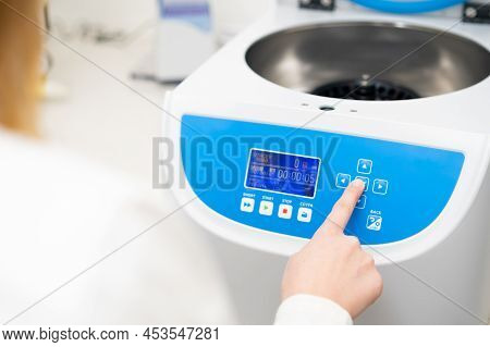 Woman Sets Parameters On The Centrifuge For Sample Preparation. Dna, Oncology Marker Analysis In Cli