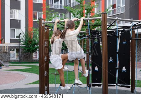 Kids Outdoors Having Fun On Modern Playground With New Colorful Equipment. Sisterhood, Friendship. T