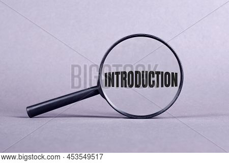 Magnifying Glass With Introduction Lettering On A Gray Background.