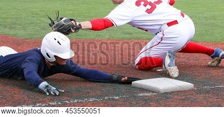 Baseball Player Sliding Head First Into Third Base Avoiding The Tag During A High School Game Close 