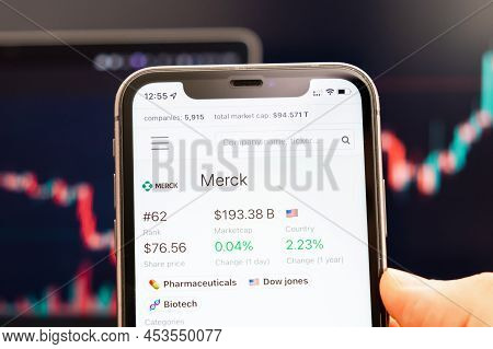 Merck Stock Price On The Screen Of Mobile Phone In Mans Hand With Changing Stock Market Graphs On Th