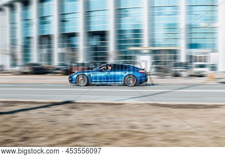 Porsche Panamera Gts Car In City Streets In Motion. Blue Porsche Panamera Is Driving On Urban Highwa