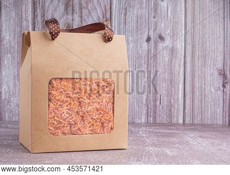 Package For Sale Of Sweet And Sour Crispy Noodles Or Mee Krob In The Thai Language Placed On A Gray 