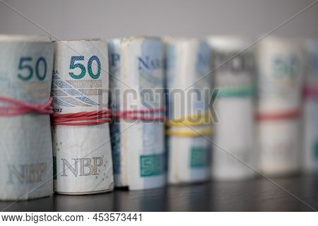 The Banknotes Rolled And Tied Together With A Rubber Band Stand On The Table Top.