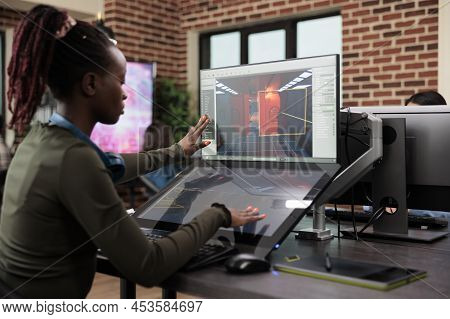 Developing Company Employee Working At Computer With Two Monitors While Editing Game Level. Creative