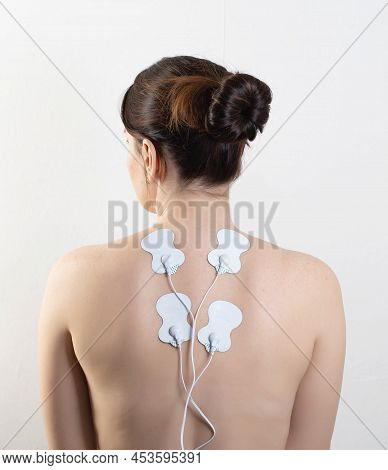 Acupuncture Electronic Massager On The Girl's Back To Relax Muscles And Relieve Back Pain. Home Phys