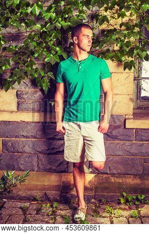 Young Man Waiting. Wearing A Green Short Sleeve Henley Shirt, Light Yellow Shorts, Leather Casual Sh