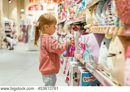 Little Caucasian Girl Coosing A New Toy In The Big Baby Store.