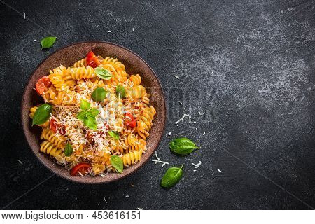 Italian Pasta Alla Arrabiata With Basil And Parmesan On Dark Table. Fusilli Pasta With Tomato Sauce.