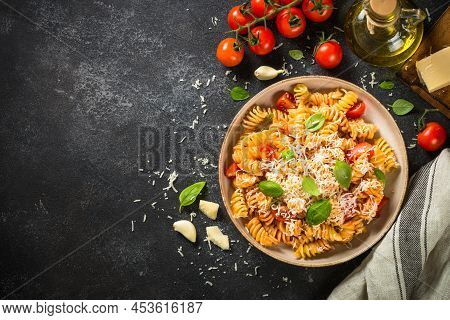 Italian Pasta Alla Arrabiata With Fresh Tomatoes, Basil And Parmesan On Black Stone Table. Top View 