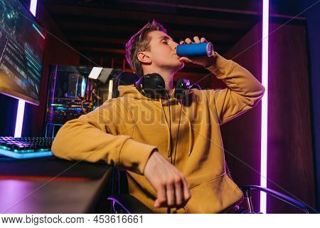 Yong Caucasian Pro Gamer Drinking Energy Drink While Playing Computer Video Games