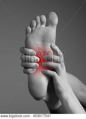 Arch Pain Caused By Inflammation, Overuse, Plantar Fascia Injury. Woman Hands Holding Foot With Red 