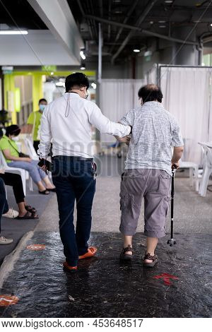 Bangkok Thailand- Feb 02,2022: Healthy Young Man Supporting An Elderly Man Walking With Cane To  Hea