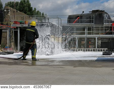 Container Fire Fighting Training. Fire Fighter Spraying Non Aspirated Foam Blanket On Smoldering Moc