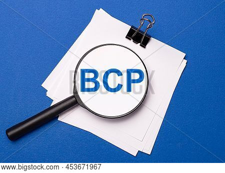 On A Blue Background, White Sheets Under A Black Paper Clip And On Them A Magnifying Glass With The 