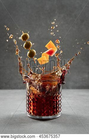 Vermouth Cocktail Splashing Out Of Glass On Light Gray Background. Vertical Format.