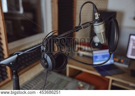 Focus On Professional Microphone And Headphones In The Blurred Soud Engineer Workplace
