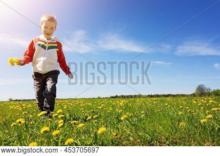 Cute Child Running Outdoors In Nature With Bunch Of Dandelions. Concept Of Childhood, Family And Mot