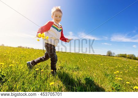 Little Child Running Outdoors In Nature With Bunch Of Dandelions. Concept Of Childhood, Family And M