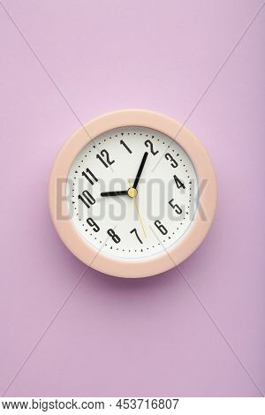 Pink Clock On Purple Background. Vertical Photo