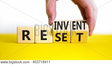 Reinvent And Reset Symbol. Businessman Turns Wooden Cubes And Changes The Concept Word Reinvent To R