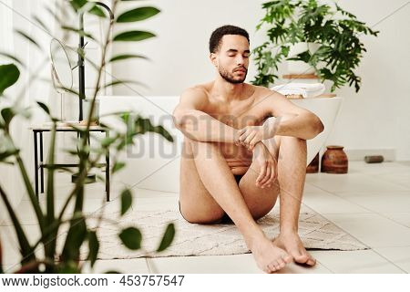 Young Shirtless An Sitting On Carpet With Eyes Closed And Doing Relaxation Exercise During Yoga In B