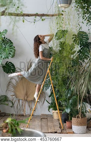 Dreamy Self-confident Woman Grows Plants, Takes Care Of Flowers, Enjoys Beauty Around In Greenhouse.