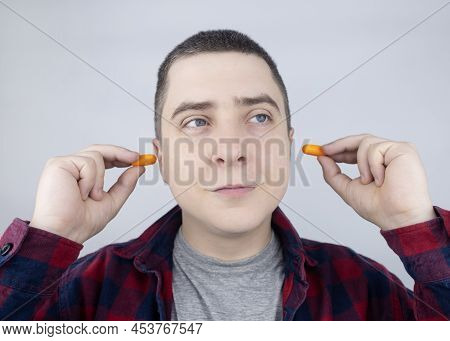 The Man Puts On Earplugs. Close-up Of An Orange Noise Barrier. Deep Sleep. The Ent Doctor Advises Or
