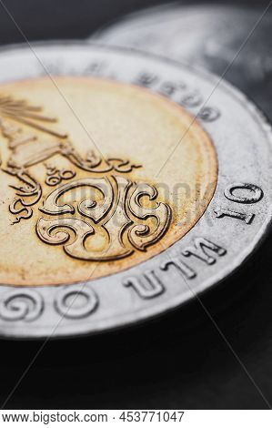 Translation: 10 Baht Thailand. Thai Coin Of 10 Baht Lie On Dark Black Surface. Economy Or Finance. L