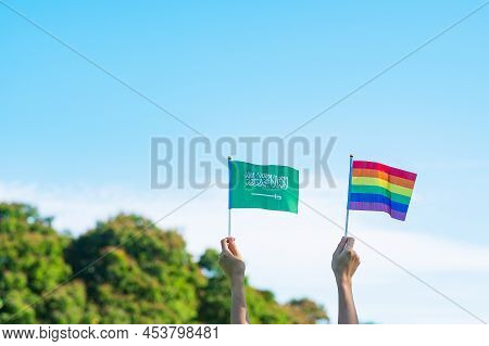 Hands Showing Lgbtq Rainbow And Saudi Arabia Flag On Nature Background. Support Lesbian, Gay, Bisexu