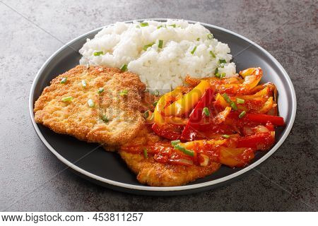 Homemade Breaded Schnitzel Served With Gypsy Sauce Of Bell Peppers And Onions With Rice In A Plate O