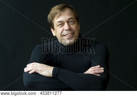 Portrait Of A Happy Blue-eyed Man 45-50 Years Old In A Golf Sweater On A Black Background, Perhaps H